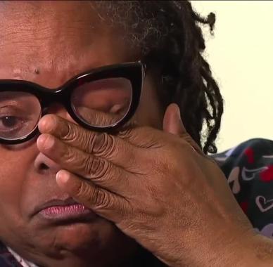 Crying woman wipes away a tear from under her glasses.